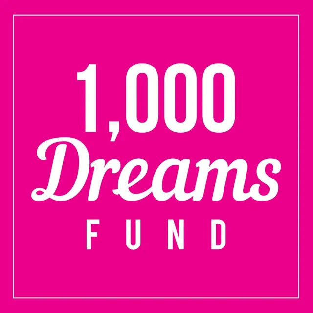 The 1,000 Dreams Fund logo: white script lettering on a shade of pink that refuses to be overlooked.